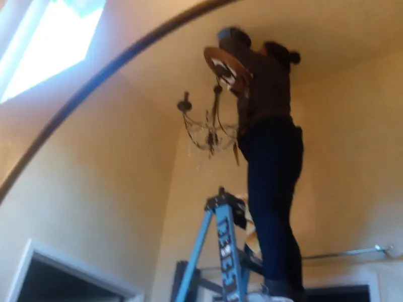Electrician installing a chandelier in a Valrico residence